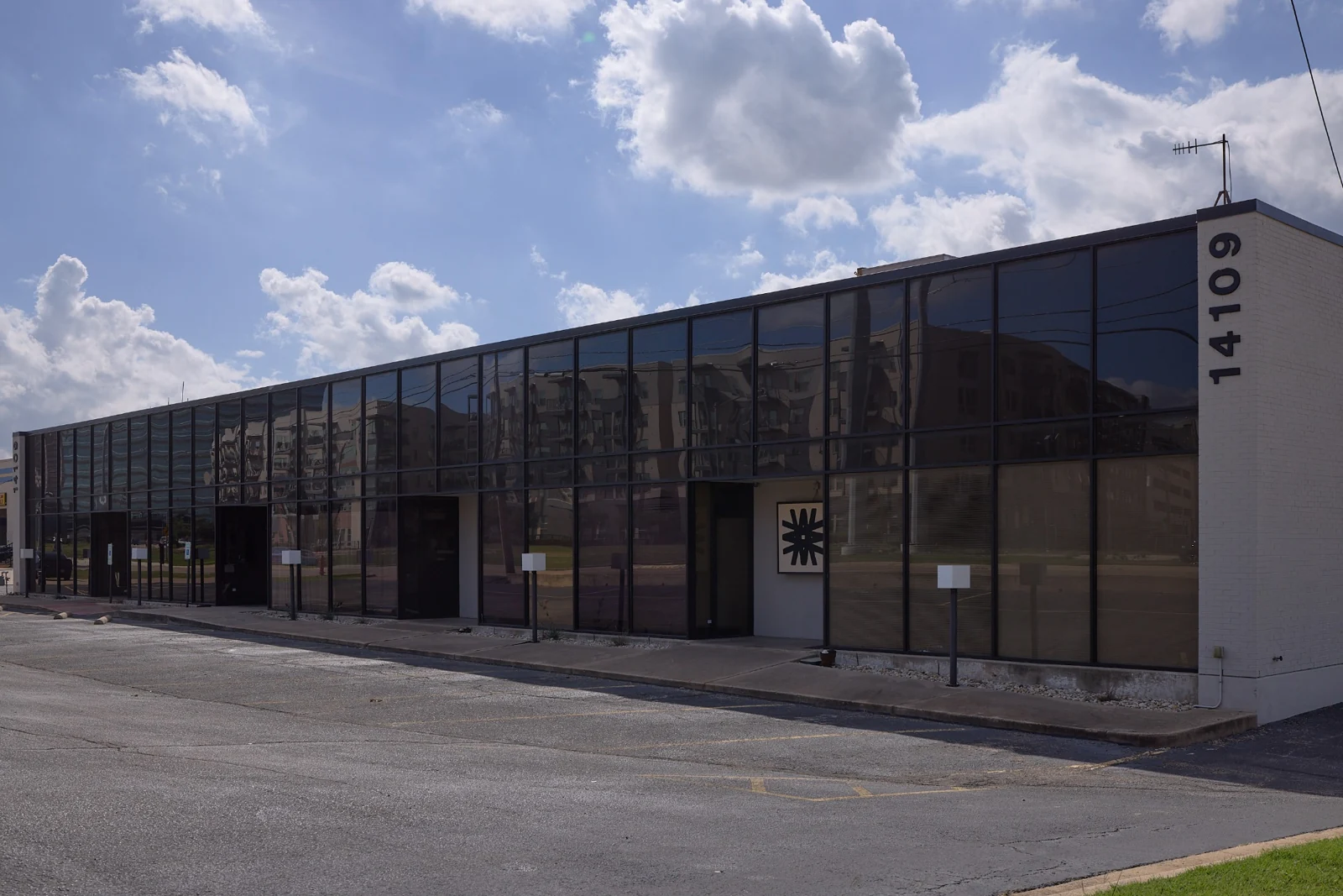Third Wave Studio’s long glass facade, reflecting trees and a blue Dallas sky.